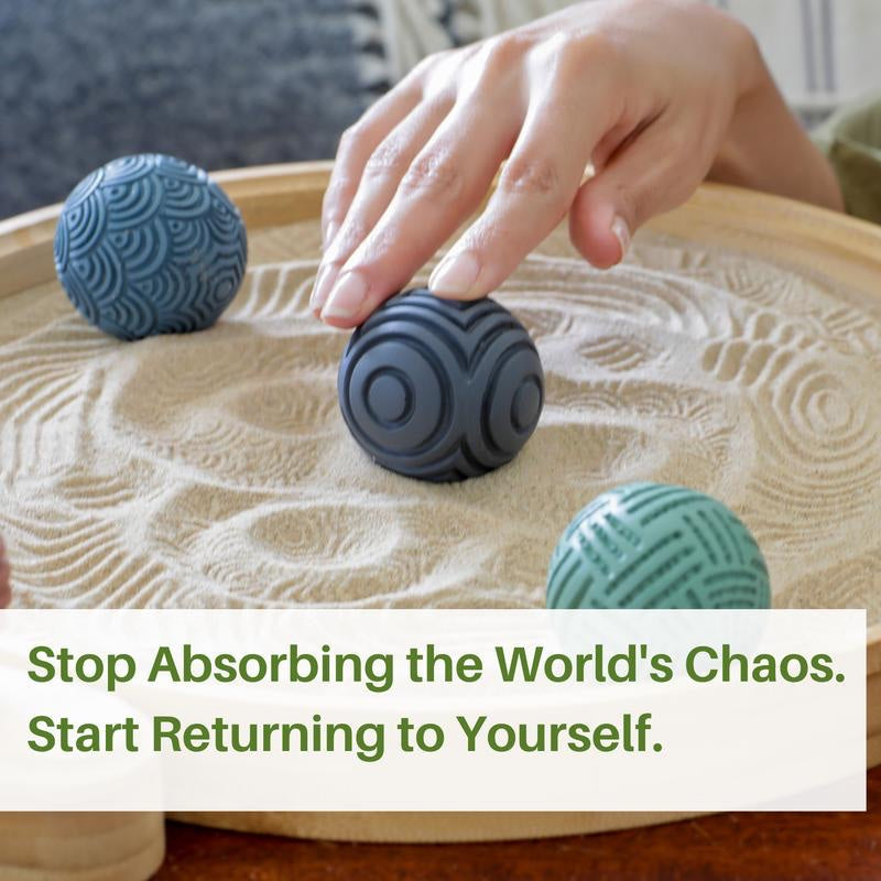 Hand rolling a textured sphere through real sand in the bamboo tray