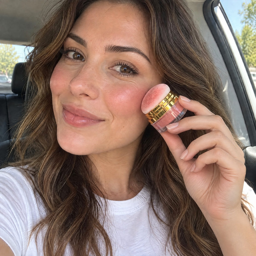 Woman in a parked car tapping the puff of the blush jar onto her cheekbone
